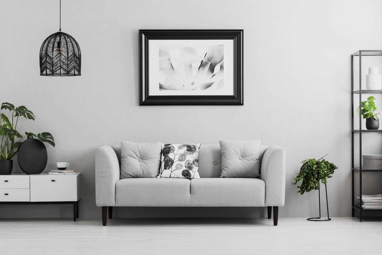 black industrial bookcase and a plant stand next to an upholster